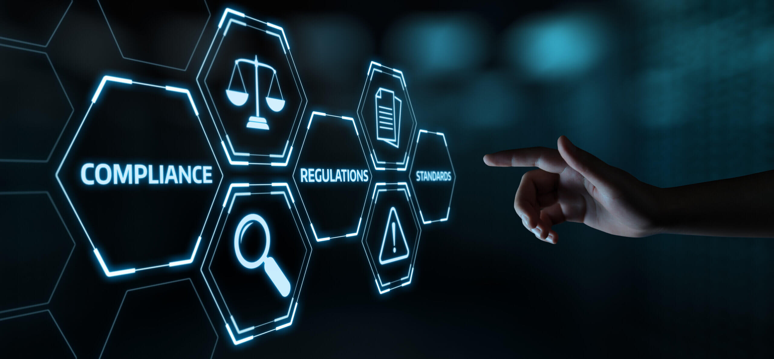 A hand pointing at digital hexagonal icons displaying the words "Compliance," "Regulations," and "Standards." Each hexagon has symbols like scales of justice, a document, and a magnifying glass, with a dark, blurred background.