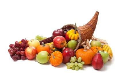 A cornucopia overflowing with assorted fruits and vegetables, including pumpkins, apples, grapes, corn, and pears, set against a white background.