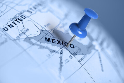 A blue pushpin marks a location in Mexico on a map. The surrounding area includes parts of the United States and other geographic details. The image has a blue tint, highlighting Mexico in focus.
