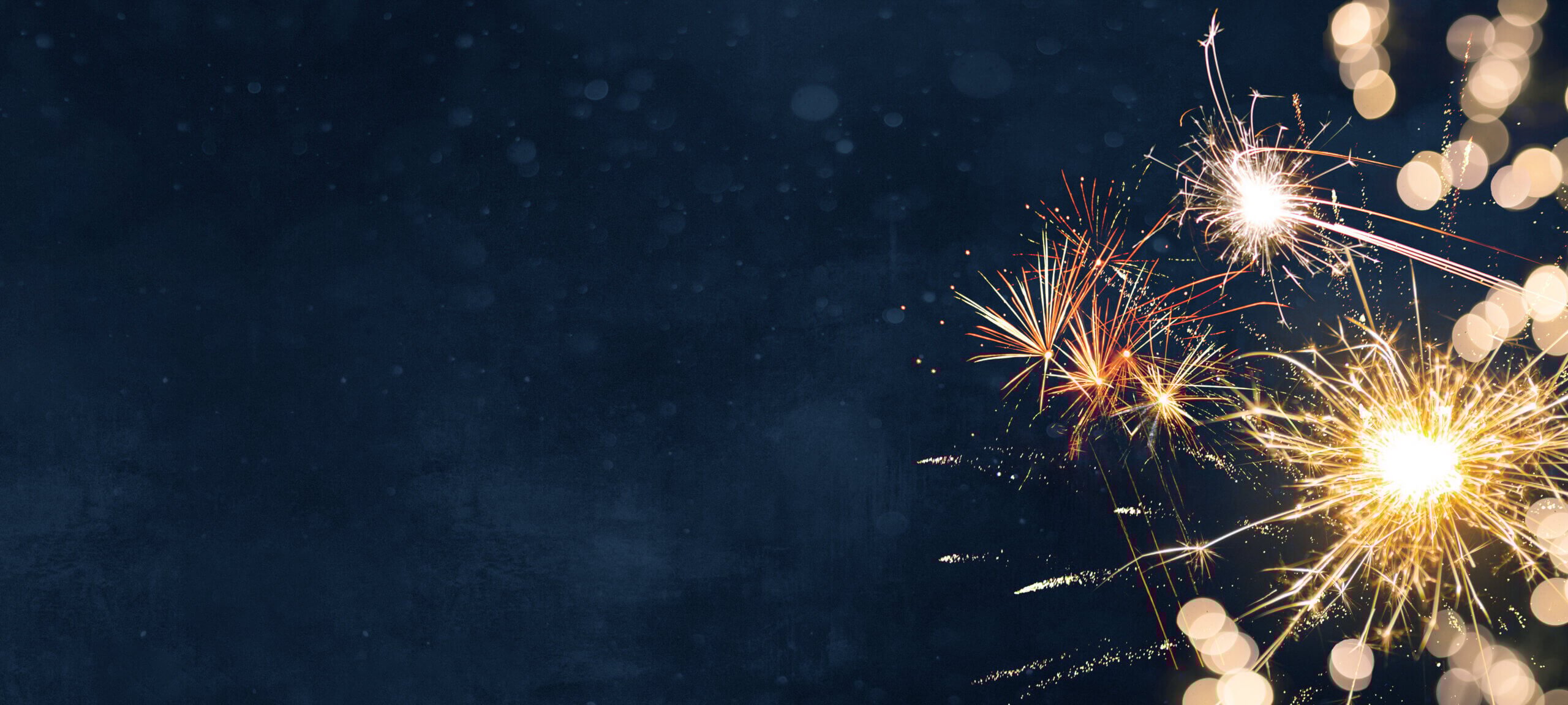 A dark blue background filled with bright, colorful bursts of fireworks on the right side. The fireworks include various types and colors, such as white, red, and gold, creating a festive and celebratory atmosphere.