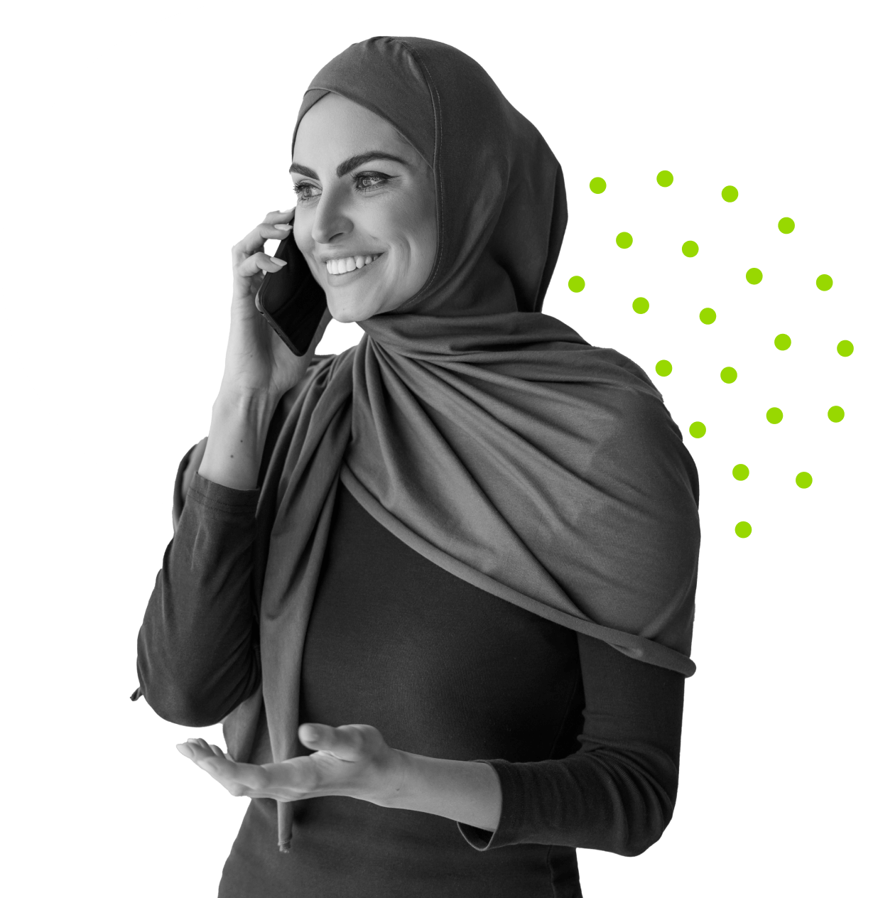 A woman in a hijab is smiling and talking on a mobile phone. She wears a long-sleeved top and gestures with her hand. The image is in black and white, with a white circle and green dots in the background.