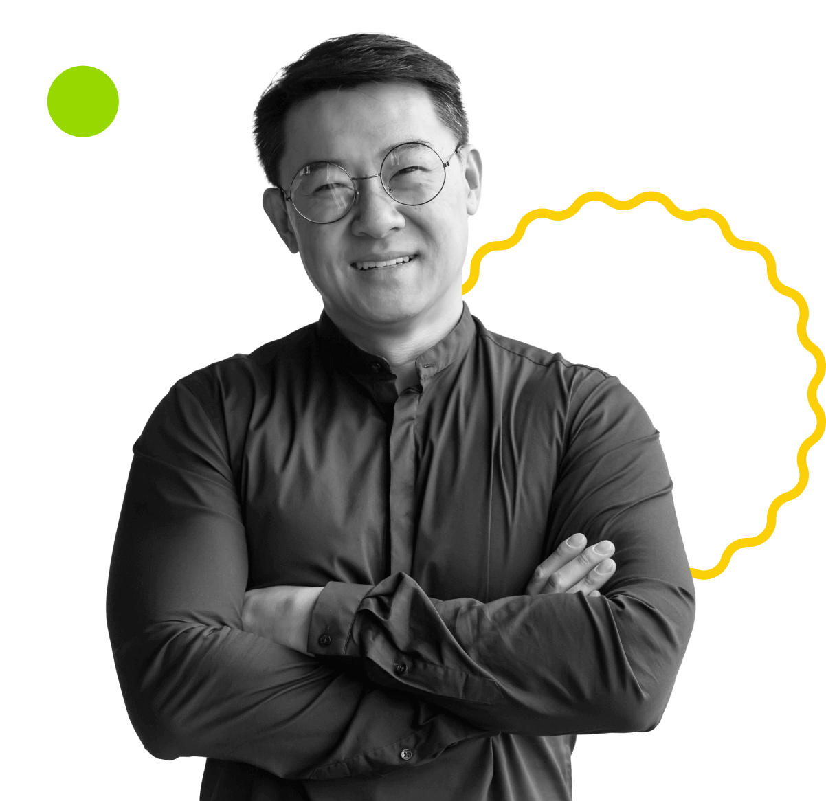 A smiling person with glasses and short hair, wearing a button-up shirt, stands with crossed arms. The background features a white circle with a green dot and a yellow wavy line.