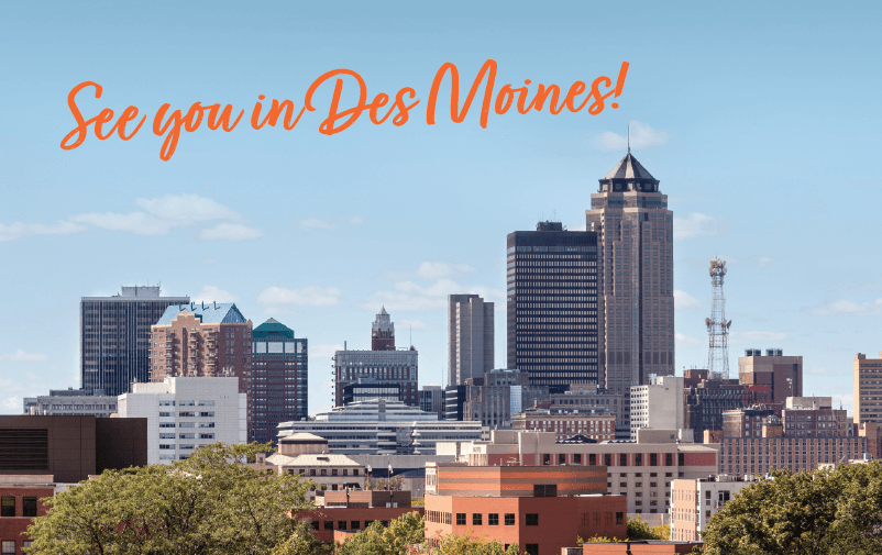 Skyline of Des Moines with various skyscrapers against a clear blue sky. The text "See you in Des Moines!" is written in orange cursive at the top. Trees are visible in the foreground.