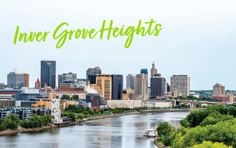 View of a city skyline with tall buildings along a river, lush green trees in the foreground, and "Inver Grove Heights" in bright green cursive at the top—perfect for promoting upcoming lending conferences 2025.